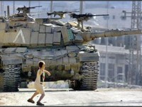 A Palestinian kid throws a rock towards an Israeli tank.