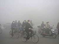 People ride along a street on a smoggy day in Daqing, Heilongjiang province. REUTERS/Stringer