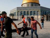 An injured woman is being carried on a stretcher after clashes broke out inside Al-Aqsa Mosque's compound [Ahamd Gharabli/AFP]